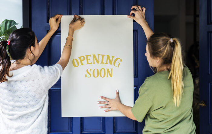 Women putting on store opening soon signQuick Reliable Printing (QRP)