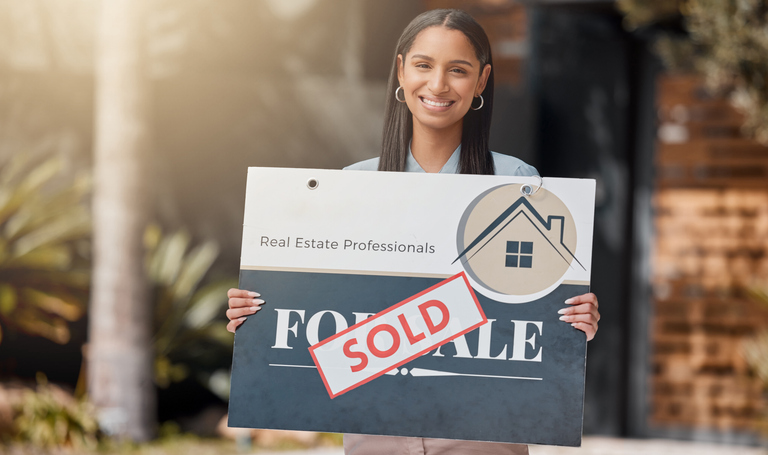 Shot of a real estate agent standing next to a sold sign outsideQuick Reliable Printing (QRP)