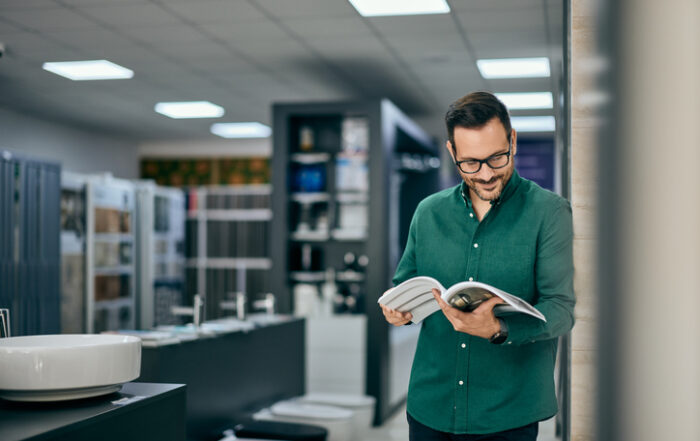 A male seller reading one of the catalogs at the home design shopQuick Reliable Printing (QRP)
