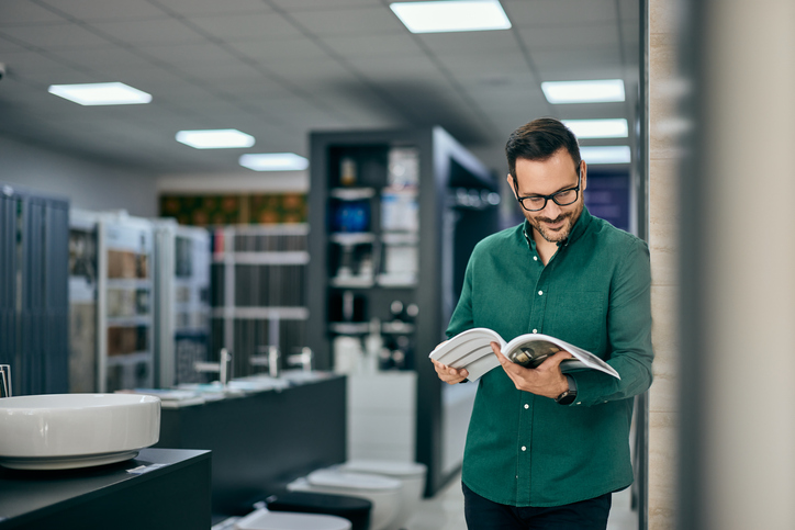 A male seller reading one of the catalogs at the home design shopQuick Reliable Printing (QRP)