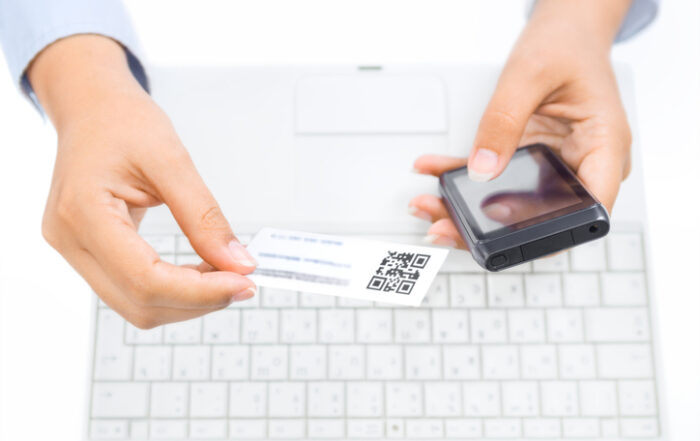Close up of hands holding smart phone and business cardQuick Reliable Printing (QRP)