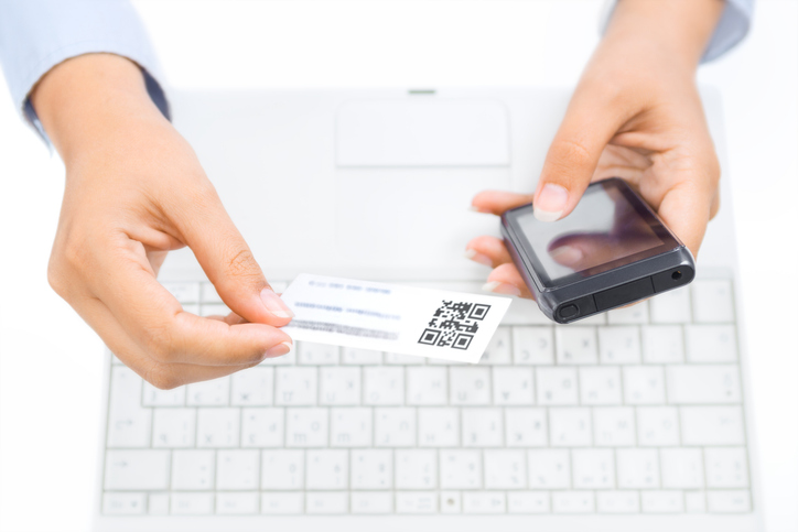 Close up of hands holding smart phone and business cardQuick Reliable Printing (QRP)