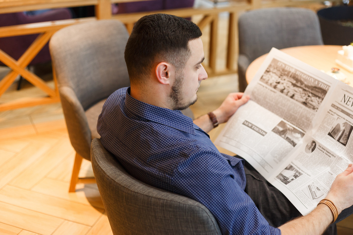 Man reading a newspaper in cafeQuick Reliable Printing (QRP)