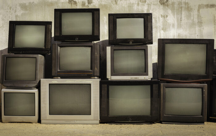 Retro old TVs pile on floor in front of old wall Stack television sets with vintage filter effectQuick Reliable Printing (QRP)