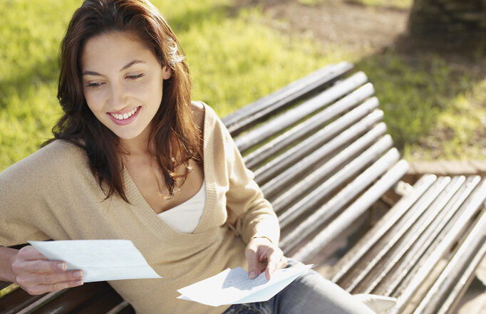 Woman sitting on a park bench reading a letter | Quick Reliable Printing (QRP) Quick Reliable Printing (QRP)