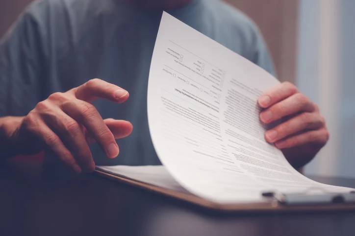Person flipping through a stack of documents on a clipboard, reviewing paperwork.Quick Reliable Printing (QRP)